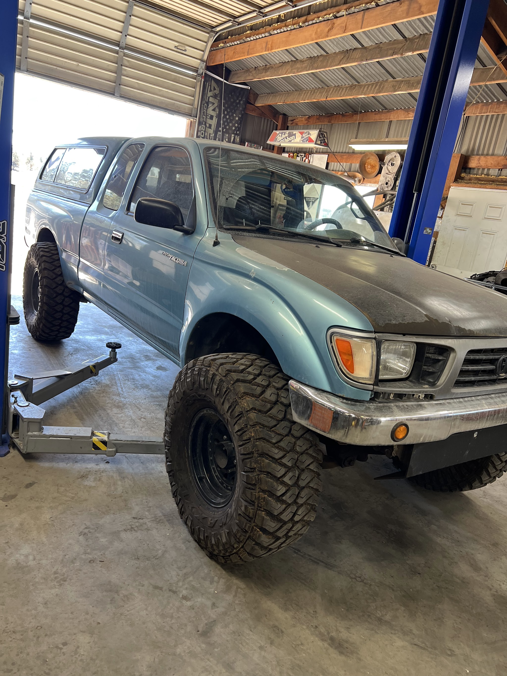 A lifted Toyota Tacoma on mud terrain tires inside the Hastings Tire & Offroad bay