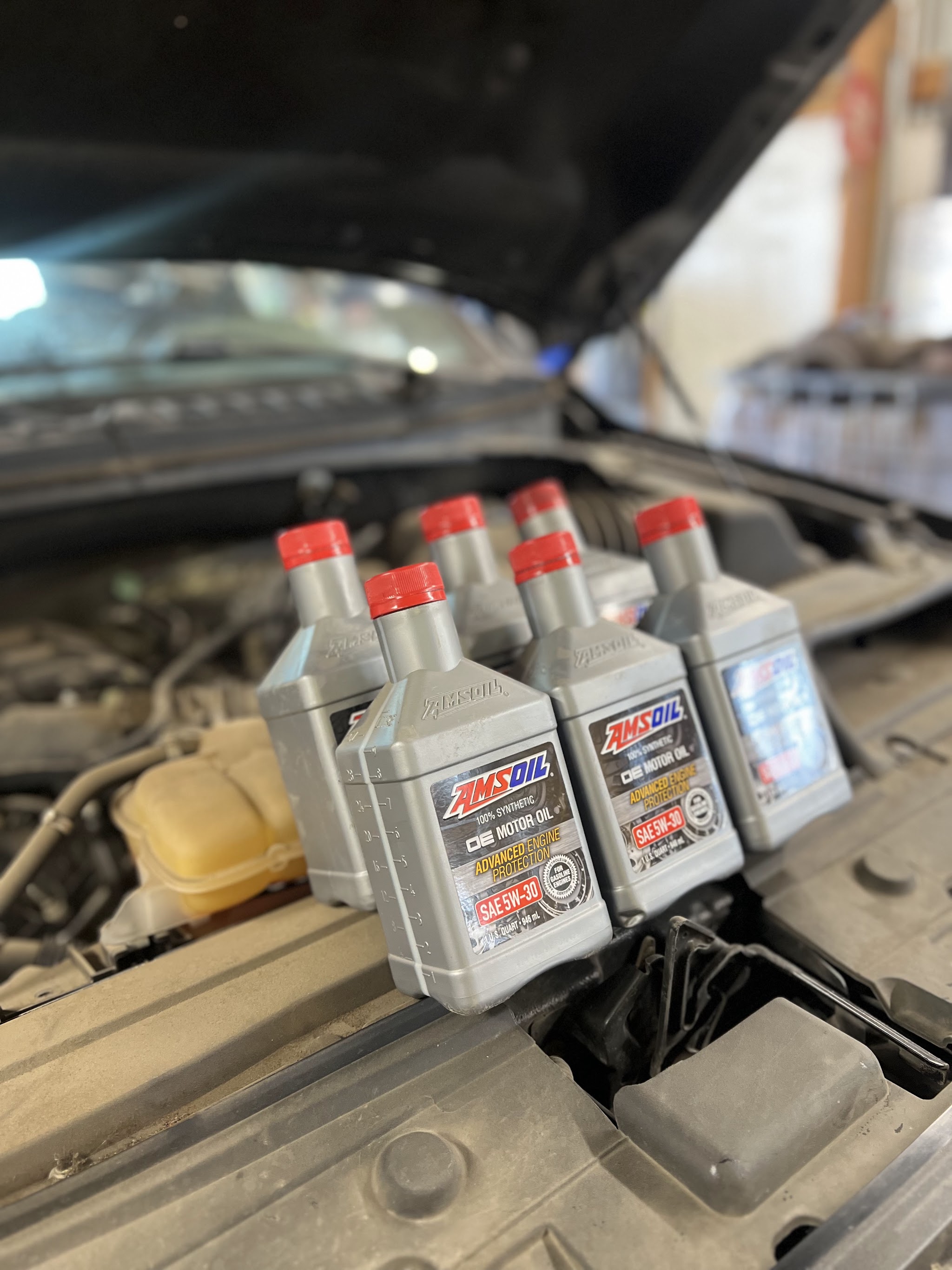 Quarts of synthetic oil lined up on an engine bay during a service